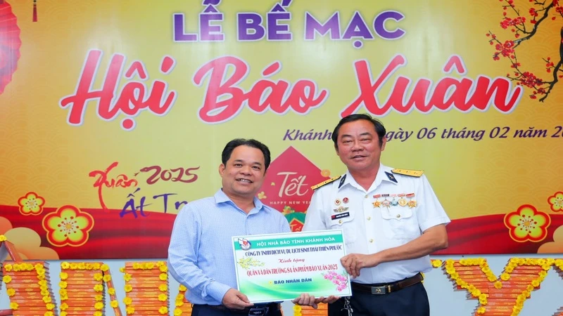 Cựu binh Trường Sa Nguyễn Văn Dũng (bên phải) tặng tượng trưng ấn phẩm Nhân Dân Xuân Ất Tỵ 2025 đến quân, dân huyện đảo Trường Sa. (Ảnh: PHONG NGUYÊN) 