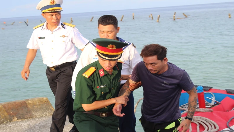 Đưa bệnh nhân Trần Văn Ưu từ tàu cá lên Bệnh xá đảo Song Tử Tây. ( Ảnh: CTV) 