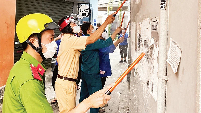 Công an, cảnh sát giao thông và các lực lượng phối hợp bóc gỡ các mẫu quảng cáo, tờ rơi dán sai nơi quy định. (Ảnh CTV) 