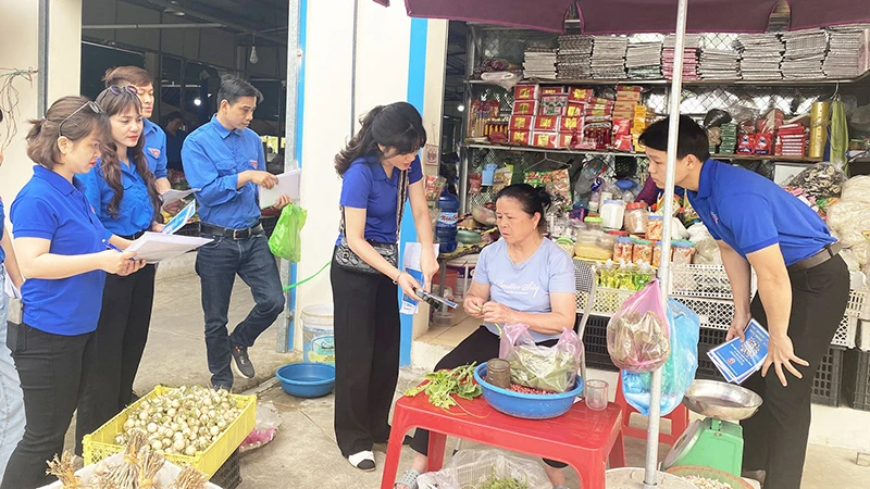 Ðoàn viên thanh niên Sở Thông tin và Truyền thông tỉnh Bắc Kạn hướng dẫn tiểu thương ở chợ sử dụng mã QR thanh toán trực tuyến. (Ảnh THU TRANG) 