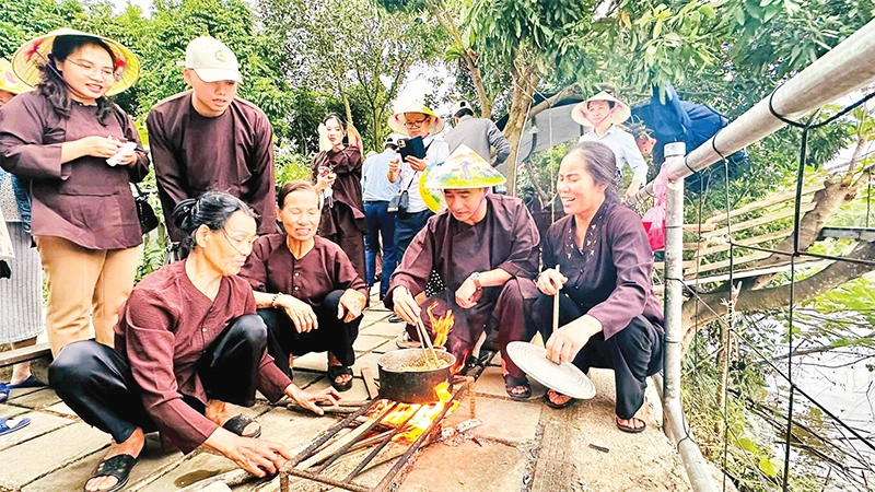 Du khách tìm hiểu các công đoạn làm bánh đúc truyền thống tại Giang Biên, quận Long Biên, TP Hà Nội. (Ảnh LINH TÂM) 