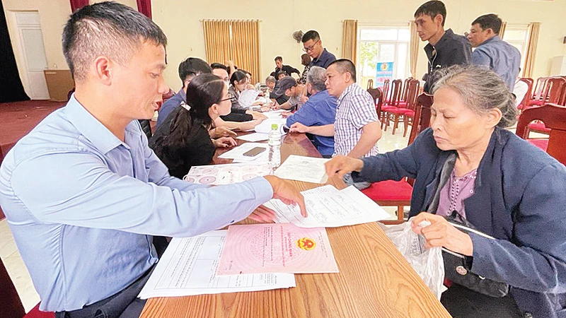 Cán bộ xã Vân Tảo hướng dẫn người dân thực hiện các thủ tục trước khi nhận tiền giải phóng mặt bằng. 