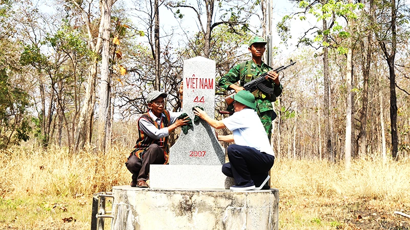 Già làng, người có uy tín xã biên giới Krông Na, huyện Buôn Ðôn (Ðắk Lắk) lau chùi cột mốc chủ quyền biên giới quốc gia trên địa bàn. 