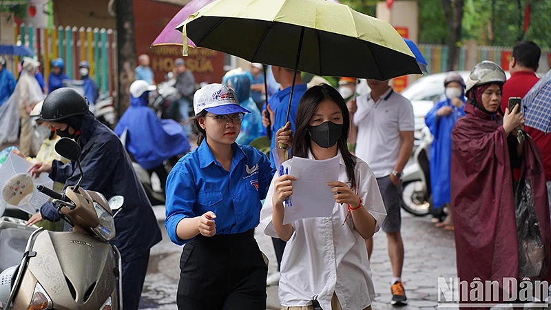 Tình nguyện viên "Tiếp sức mùa thi" năm 2023 hỗ trợ thí sinh dưới cơn mưa.