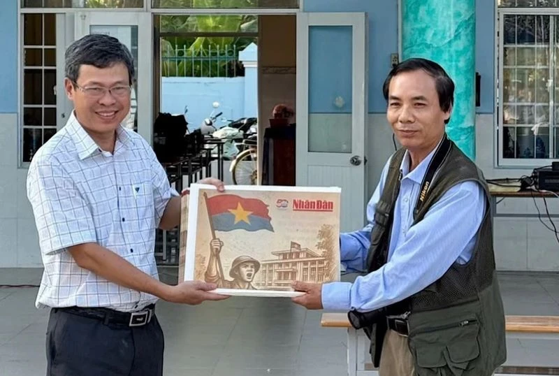 Nhà báo Trọng Duy, đại diện Văn phòng Báo Nhân Dân tại Bạc Liêu trao Phụ san đặc biệt của Báo Nhân Dân đến thầy giáo Dương Bình, Bí thư Chi bộ, Hiệu trưởng Trường Trung học phổ thông Chuyên Bạc Liêu.