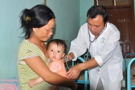 Cán bộ y tế khám bệnh cho trẻ em ở Trạm y tế xã Thoong Pé.