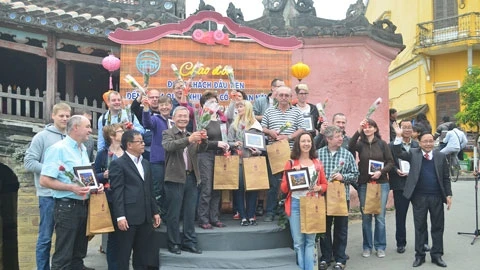 Ông Đinh Hài, giám đốc Sở VH-TT&DL (ngoài cùng bìa phải) trao quà và chụp ảnh lưu niệm với 21 vị khách đến xông đất tại Hội An.