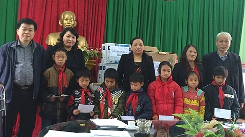 Đại diện Báo Nhân Dân tặng quà cho đại diện UBND và các em học sinh Trường Tiểu học xã Quy Kỳ.