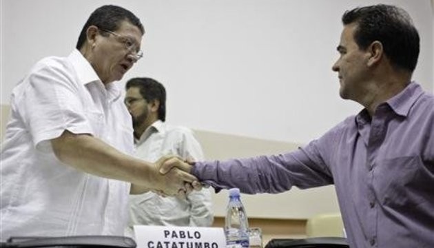 Thành viên trong đoàn đàm phán của FARC, Pablo Catatumbo (bên trái), bắt tay với thành viên đoàn đàm phán của Chính phủ Colombia, Frank Pearl, trong cuộc họp báo được tổ chức tại Havana, Cuba, ngày 26