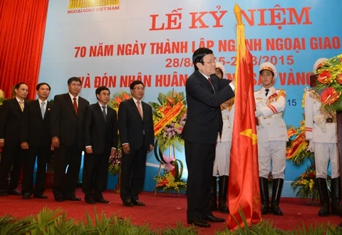 Chủ tịch nước Trương Tấn Sang gắn Huân chương Sao vàng lên lá cờ truyền thống của ngành ngoại giao. Ảnh: DUY LINH