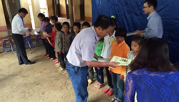 Nhà báo Quốc Hồng trao sách giáo khoa cho các em học sinh trường tiểu học Tả Gia Khâu.