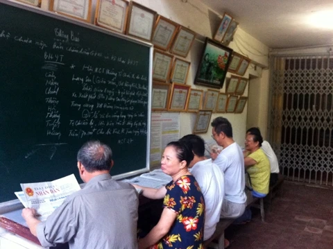Người dân đọc báo tại cầu thang văn hóa khu tập thể A3, phường Nghĩa Tân (Cầu Giấy).