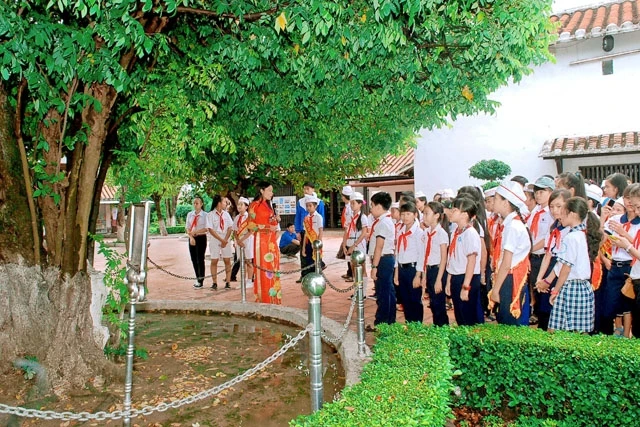 Các em học sinh nghe giới thiệu về cây khế được thầy giáo Nguyễn Tất Thành chăm sóc trong thời gian dạy học tại Trường Dục Thanh.
