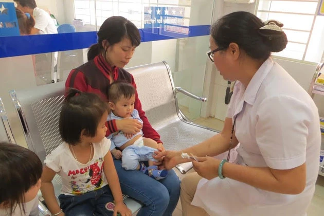 Người dân TP Buôn Ma Thuột đưa con em mình đến Trung tâm Y tế dự phòng tỉnh Đác Lắc tiêm vắc-xin phòng chống viêm não Nhật Bản B. 