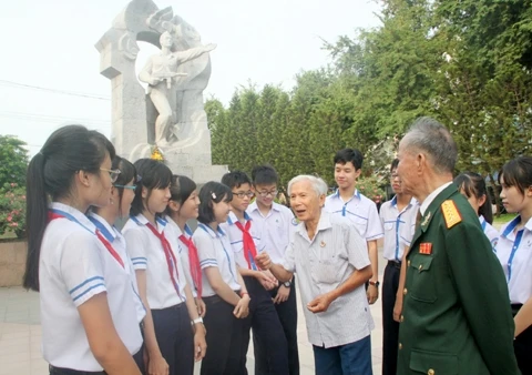 Các cháu học sinh và các cựu chiến binh mặt trận 23-10 bên tượng đài Võ Văn Ký. (Ảnh: XUÂN THÀNH)