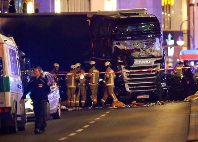 Cảnh sát và các nhân viên cứu hộ đứng cạnh một chiếc xe tải bị đâm tại hiện trường vụ tai nạn, ở Berlin, Đức, tối ngày 19-12-2016. (Ảnh: Reuters)