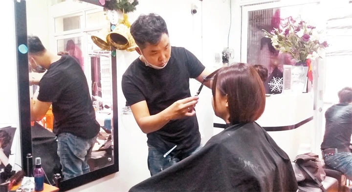 Nguyễn Thái Thành cắt tóc cho khách hàng.