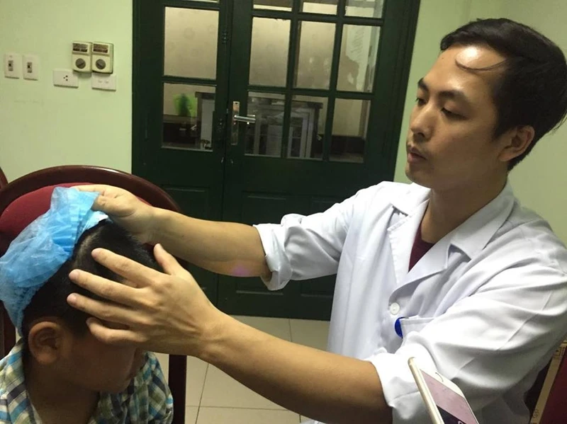 Bác sĩ Trần Đình Văn đang khám lại cho bé Nguyễn Đình P. ngày 8-5. 