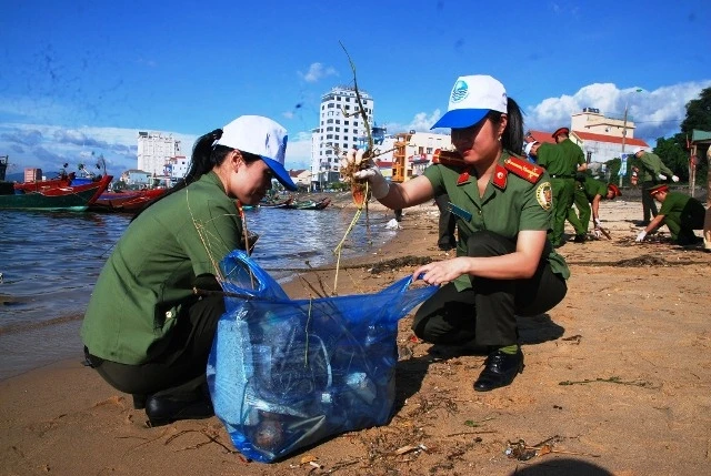 Các đoàn viên Công an tỉnh Quảng Bình thu dọn rác bên bờ sông Nhật Lệ (Ảnh: Hương Giang)