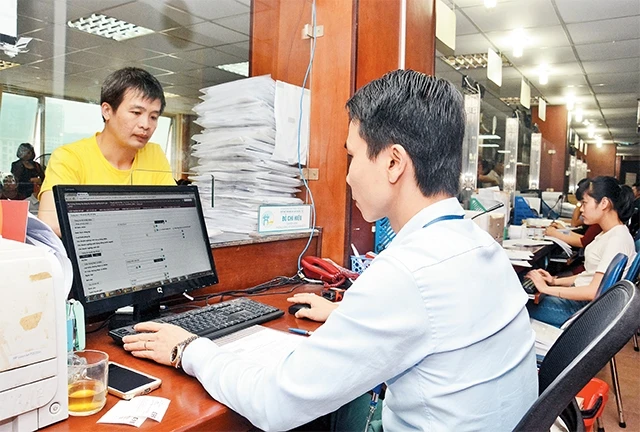 Cán bộ Phòng Ðăng ký kinh doanh (Sở Kế hoạch và Ðầu tư Hà Nội) làm thủ tục cấp giấy chứng nhận đăng ký kinh doanh cho doanh nghiệp. Ảnh: MINH HÀ
