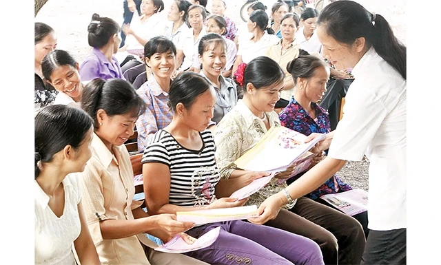 Cán bộ dân số phát tờ rơi tuyên truyền về giới tính cho người dân ngoại thành Hà Nội.
