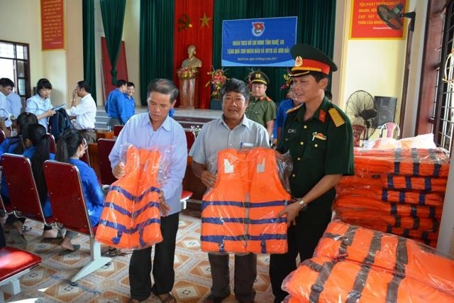 Trung tá Lê Anh Tuấn, Phó Chủ nhiệm Chính trị Bộ CHQS tỉnh Nghệ An tặng áo phao và quà cho đại diện cán bộ xã Sơn Hải.