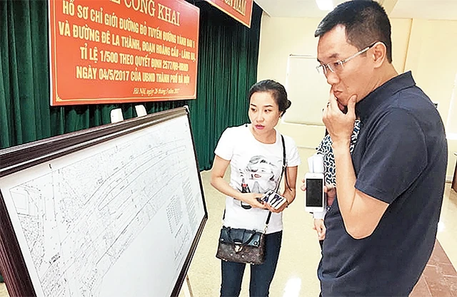 Người dân xem bản vẽ quy hoạch chỉ giới đường đỏ tuyến đường Vành đai 1 và đường Ðê La Thành đoạn Hoàng Cầu - Láng Hạ. Ảnh: TRẦN LONG