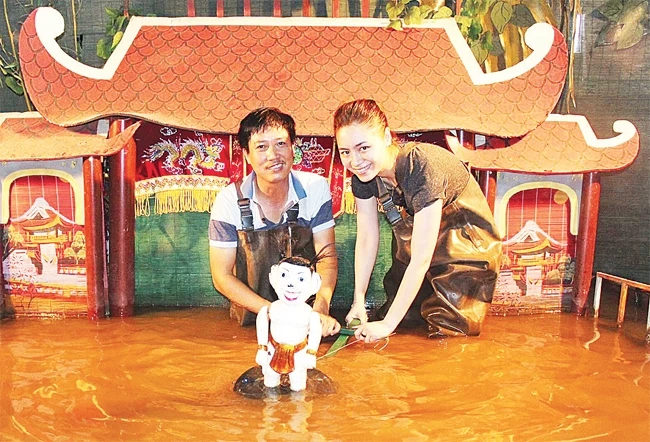 Nghệ nhân Phan Thanh Liêm (bên trái) hướng dẫn khách tham quan biểu diễn rối nước.