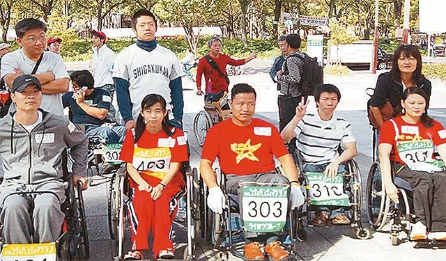 Anh Trịnh Công Thanh (người ngồi giữa) và chiếc xe lăn tự chế tạo tại một cuộc đua dành cho người khuyết tật tổ chức tại Nhật Bản.