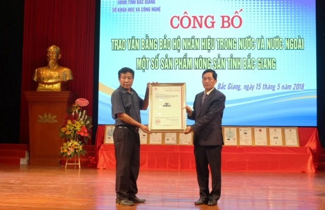 Thứ trưởng Khoa học và Công nghệ Trần Văn Tùng (phải) trao Văn bằng bảo hộ nhãn hiệu trong và ngoài nước cho tỉnh Bắc Giang.