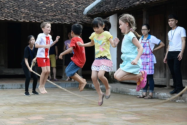 Các em nhỏ người nước ngoài hào hứng tham gia trò chơi truyền thống trong chuyến tham quan tại Bảo tàng Dân tộc học Việt Nam. Ảnh: THỦY NGUYÊN
