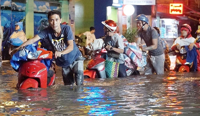 Người dân đẩy xe qua đoạn ngập sâu trên đường Phan Huy Ích (TP Hồ Chí Minh) sau cơn mưa to chiều tối 19-5. Ảnh: VĂN CHÂU