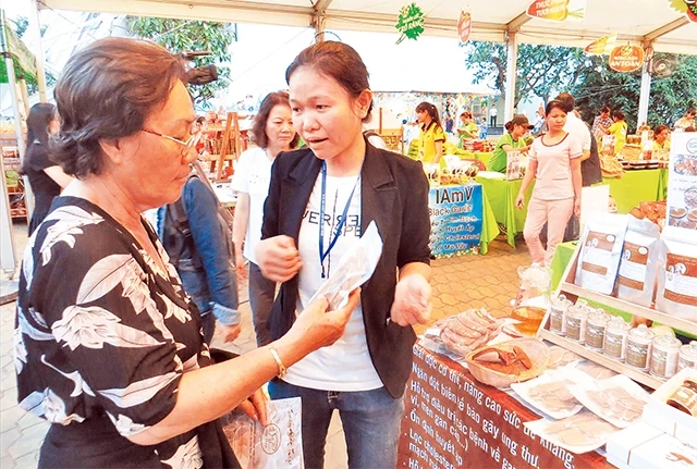 Chị Nguyễn Thị Hiếu (người bên phải) giới thiệu sản phẩm nấm linh chi của mình với khách hàng tại Hội chợ hàng Việt Nam chất lượng cao năm 2018.