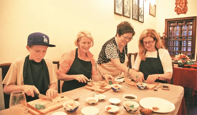 Nghệ nhân ẩm thực Phạm Thị Ánh Tuyết hướng dẫn du khách nước ngoài chế biến món ăn theo phong cách người Hà Nội. Ảnh: linh tâm