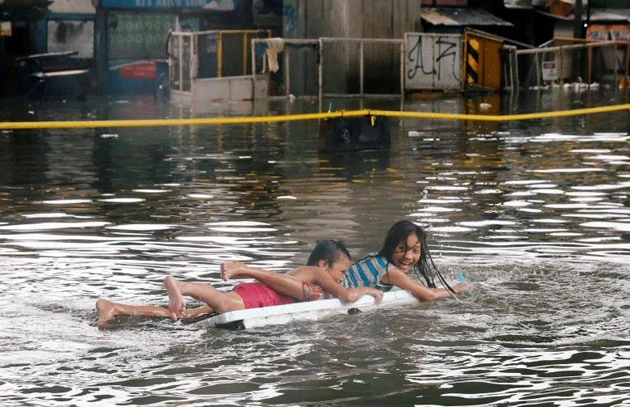 Trẻ em Manila trên một chiếc bè chơi dọc theo con đường ngập nước do mưa gió mùa từ bão nhiệt đới Sơn Tinh ở thành phố Quezon, Metro Manila Philippines.