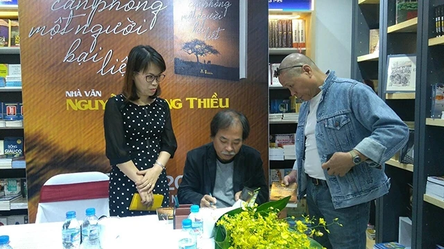 Nhà thơ Nguyễn Quang Thiều ký tặng sách trong một cuộc ra mắt. Ảnh: QUANG HƯNG