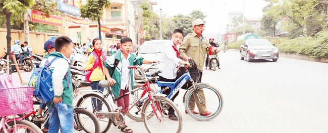 Thành viên Tổ dân phòng phường Trung Sơn Trầm đưa các em học sinh qua đường sau giờ tan học.