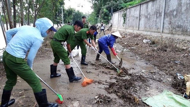 Các chiến sĩ Công an huyện Chương Mỹ giúp nhân dân xã Nam Tiến dọn rác khu vực nước rút.