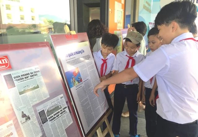 Học sinh Trường THCS Hoàng Sa Đà Nẵng xem bài trên Báo Nhân Dân được trưng bày tại triển lãm.