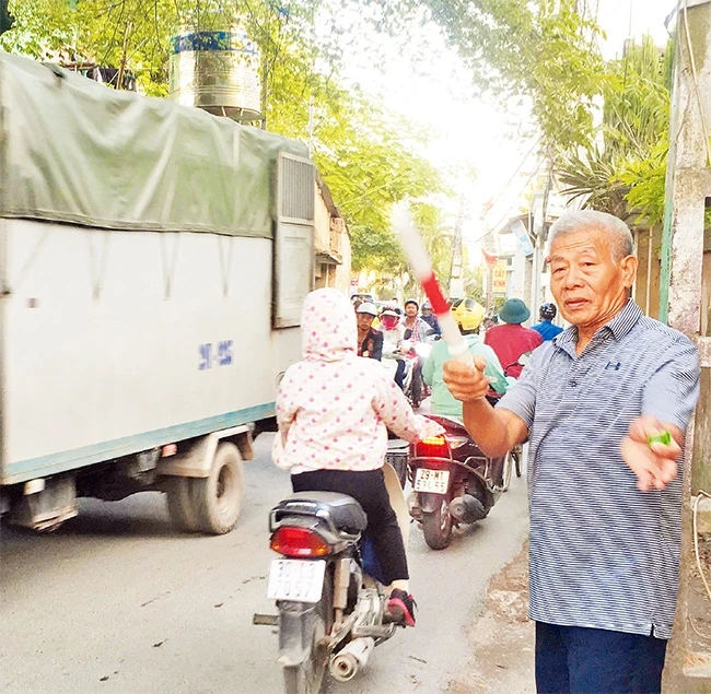Ông Lưu Viết Thục điều hành giao thông trên tuyến đường liên thôn Hữu Lê.