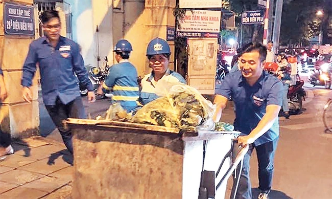 Đoàn viên, thanh niên tham gia thu gom rác với các nữ công nhân vệ sinh môi trường. Ảnh: VƯƠNG ĐỨC