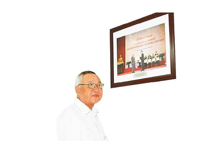 Nhạc sĩ Hình Phước Long bên tấm hình Lễ trao Giải thưởng Hồ Chí Minh, Giải thưởng Nhà nước về Văn học Nghệ thuật.