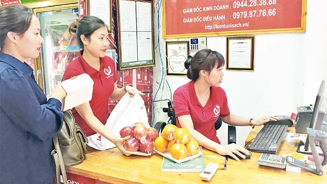 Người tiêu dùng mua trái cây tại một cửa hàng được gắn biển nhận diện bảo đảm an toàn thực phẩm ở Hà Nội.