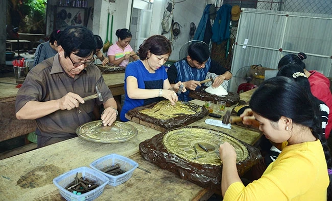 Nghệ nhân Đinh Quang Thắng (ngoài cùng bên trái) tại xưởng sản xuất ở làng nghề chạm bạc Đồng Xâm (xã Hồng Thái, huyện Kiến Xương, Thái Bình).