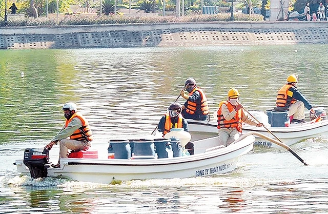 Công nhân Công ty TNHH MTV Thoát nước Hà Nội rắc chế phẩm Redoxy -3C làm sạch hồ Nghĩa Tân.