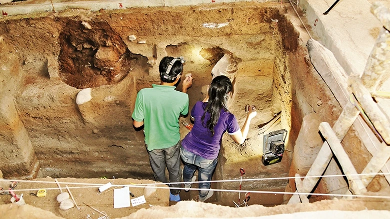 Tìm kiếm di vật tại hố khai quật của hang C6-1.