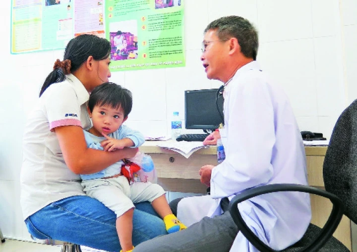 Bác sĩ tăng cường từ tuyến trên về trạm y tế phường 13 (quận Bình Thạnh) khám sàng lọc cho bệnh nhi trước tiêm chủng.