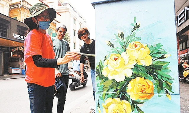 Thành viên Câu lạc bộ Hanoi Art Space vẽ trang trí bốt điện trên phố Tràng Tiền. Ảnh: HỒNG PHÚ