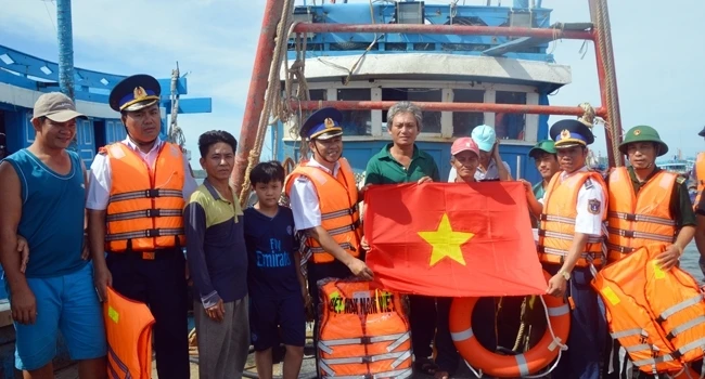 Đại diện tổ công tác Bộ Tư lệnh Vùng Cảnh sát biển 1 (Bộ Tư lệnh Cảnh sát biển Việt Nam) trao cờ Tổ quốc, áo phao tặng các ngư dân huyện đảo Cô Tô (Quảng Ninh) tháng 8-2018.