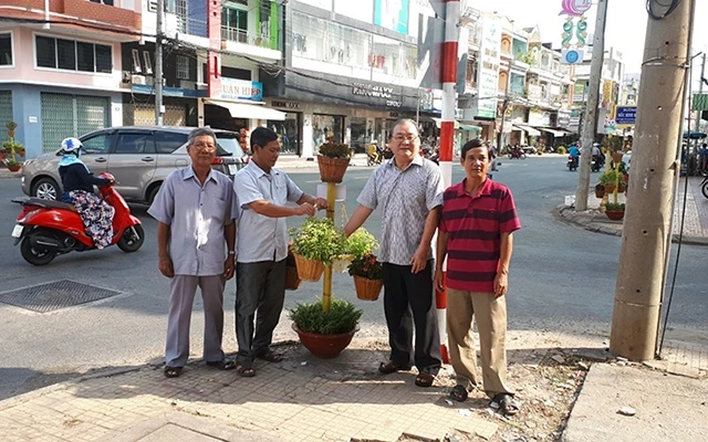 Ông Võ Thanh Liêm (thứ hai từ phải qua) cùng thành viên Tổ nhân dân tự quản số 28 trang trí lại kệ đặt giỏ hoa trên hè phố.